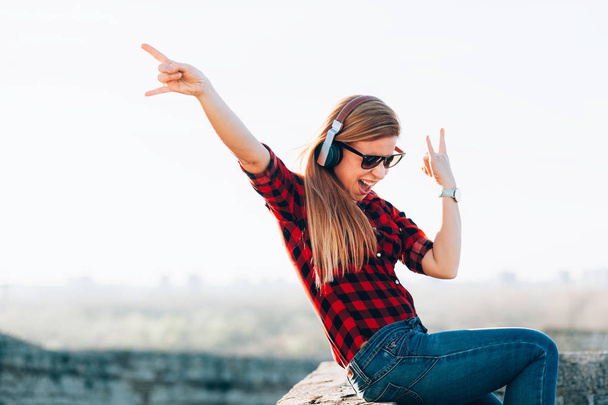 Молодая женщина слушает музыку в наушниках на открытом воздухе
 - Фото, изображение