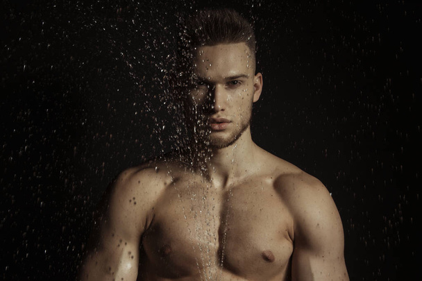 Handsome sport sexy stripped guy portrait in water drops on isolated black background - Фото, изображение
