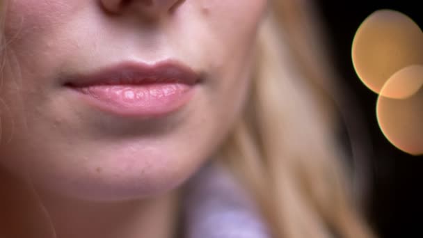 Съемки крупным планом взрослых привлекательных белокурых кавказских женских губ, соблазнительно улыбающихся боке-огнями на заднем плане
 - Кадры, видео