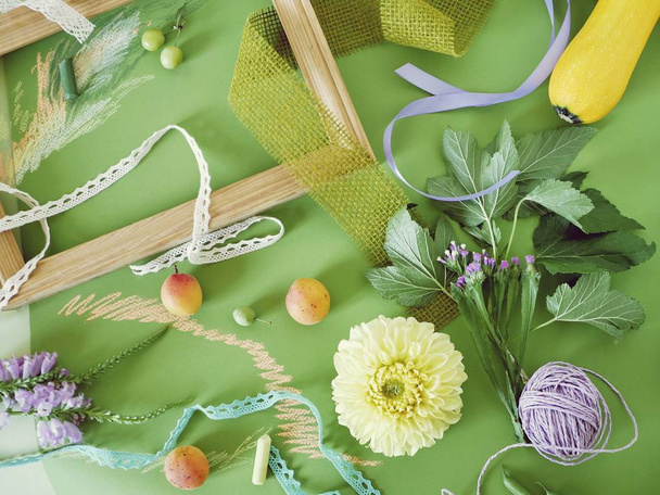 Decoratieve seizoensgebonden samenstelling van fruit, decor, groen en een houten leeg frame op groen getint papier, beschilderd met pastel, bovenaanzicht - Foto, afbeelding