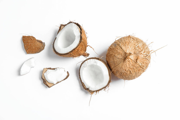 Kaksi kookospähkinää joista toinen halkaistu valkoisella pohjalla
 - Valokuva, kuva