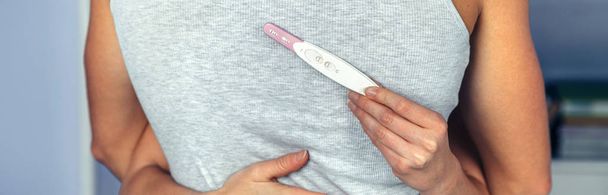 Ζευγάρι αγκαλιάζει ενώ γυναίκα χέρι που κρατά το τεστ εγκυμοσύνης - Φωτογραφία, εικόνα