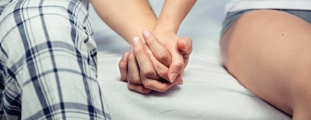 Jeune couple tenant la main assise sur un lit
 - Photo, image