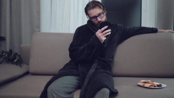 Handsome bearded man relaxing on sofa - Footage, Video