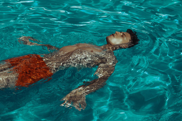 Sterk gezicht spier mannelijk model op de vakantie zwembad achtergrond met blauw water op het strand op de zonsondergang - Foto, afbeelding