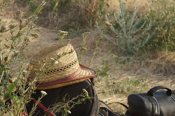 Slaměný klobouk spočívá na spřádání a tašky na březích řeky - Fotografie, Obrázek