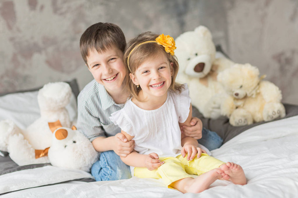 Brother and sister playing with teddy bear in bed - Foto, Bild