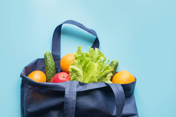 Zero waste concept. Blue shopping textile bag with fresh orange and vegetables. Space for text. - Foto, Bild