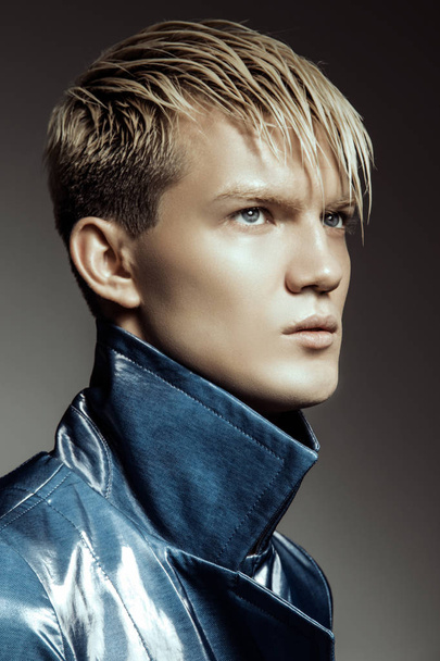 Handsome stripped blonde male model wearing blue coat on grey isolated font background - Valokuva, kuva