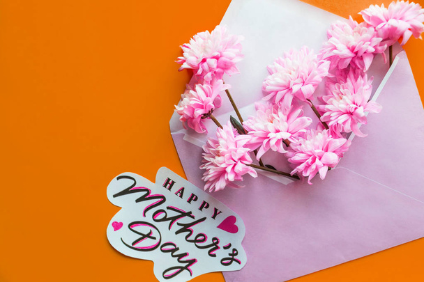 floral greeting card concept, flat lay. mothers day. tender spring image.Pink envelope full of various flowers. Flat lay. Love concept.greeting card on orange background.Pink blossoms - Foto, imagen