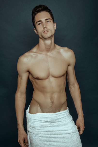 Strong stripped muscle male model with white towel on blue isolated font background - Zdjęcie, obraz