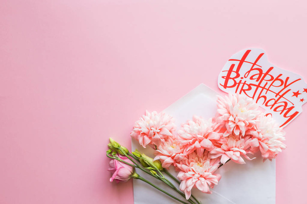 weißer Umschlag mit Frühlingsblumen. flache Lage, Aufsicht.Glückwunschkarte zum Geburtstag mit Chrysanthemen - Foto, Bild