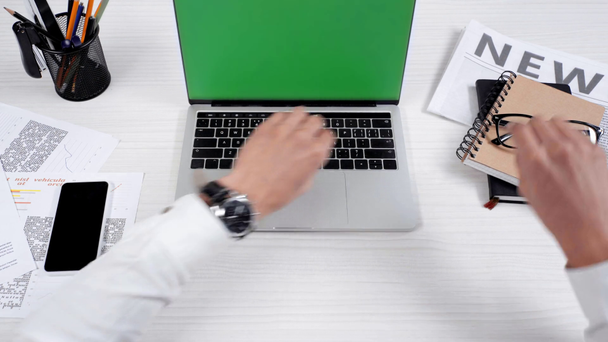 Teilbild eines Geschäftsmannes, der sein Smartphone auf den Tisch legt, den Laptop öffnet und eine Brille aufsetzt - Filmmaterial, Video