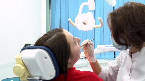 Woman at the dentist while treatment process at the dental clinic, work of stomatologist with patient. Dentist and patient in dentist office, medicine concept. - Footage, Video