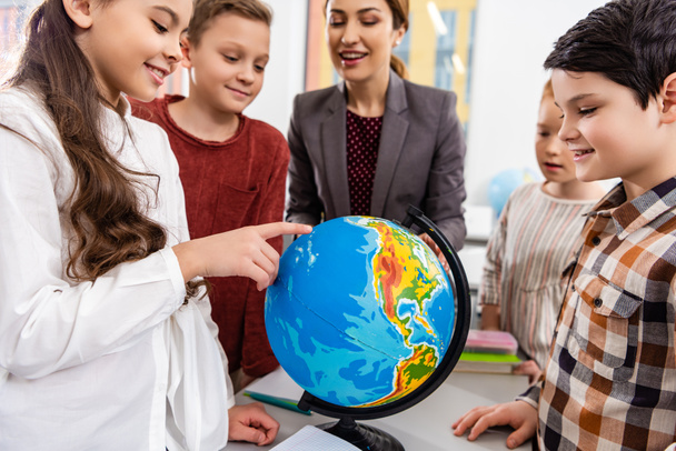 Teacher and pupils looking at globe while studying geography in classroom - Foto, Imagem