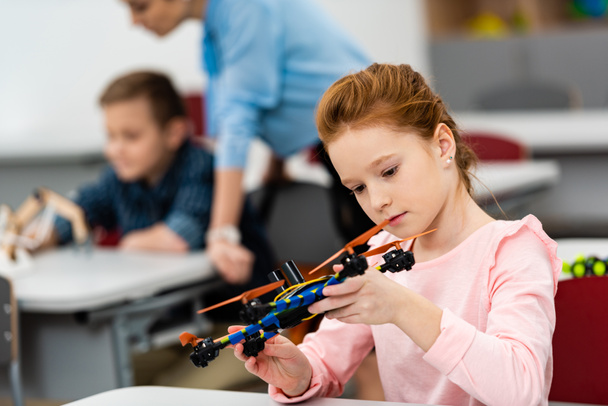 Ginger school meisje spelen met educatief speelgoed tijdens les in de klas - Foto, afbeelding