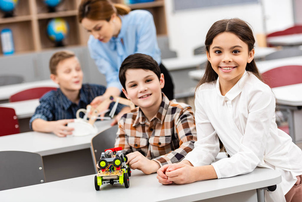 Ученики сидят за столом с игрушками во время урока в классе
 - Фото, изображение