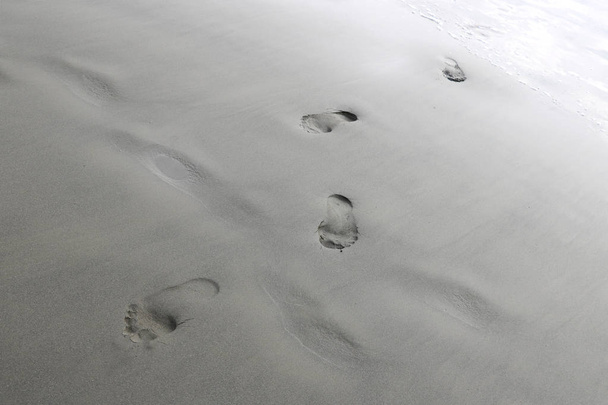 Impronte dei piedi di una donna o di un uomo sulla sabbia della spiaggia. - Foto, immagini