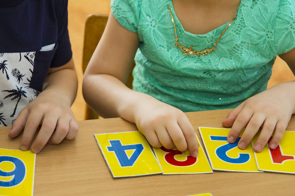 Kids are playing. Educational games. A child in kindergarten. The hands of a child. Maths. Cards for development - Fotó, kép