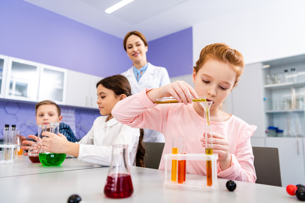 Alumnos con frascos haciendo experimento químico durante la lección de química
 - Foto, Imagen