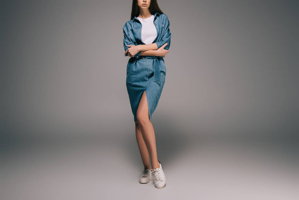 cropped view of young adult woman in denim dress with crossed arms  - Foto, afbeelding