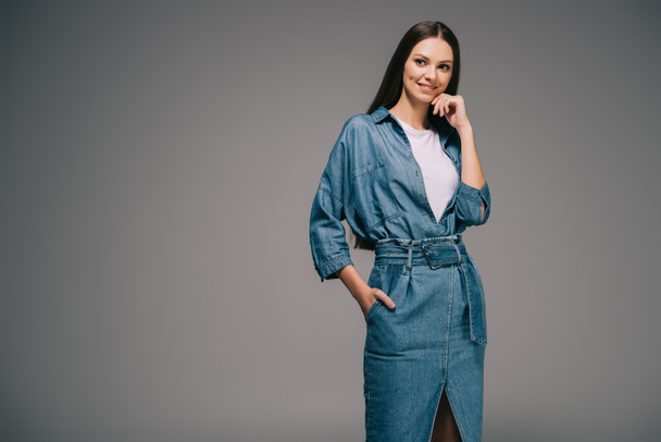 smiling and beautiful woman in denim dress with hand in pocket looking away - Valokuva, kuva