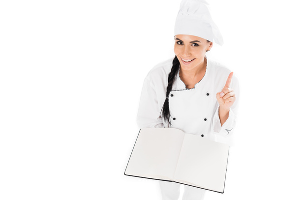 Usmívající se šéfkuchařem podniku otevřená kniha a ukazuje myšlenky gesto izolované na bílém - Fotografie, Obrázek
