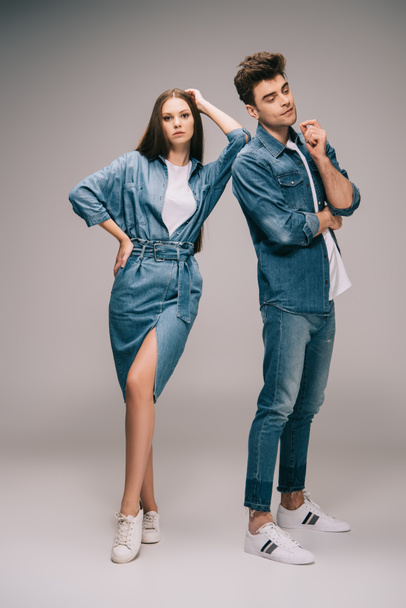 beautiful girlfriend in denim dress and handsome boyfriend in jeans and shirt on grey background  - 写真・画像