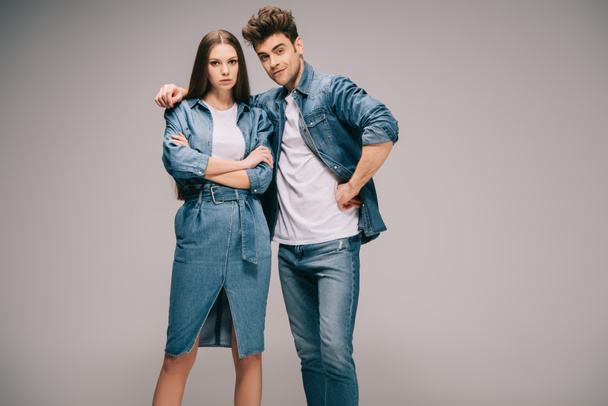attractive girlfriend in denim dress and boyfriend in jeans and shirt hugging and looking at camera  - Fotografie, Obrázek