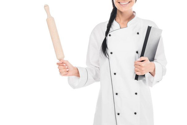 Vue recadrée du chef en uniforme tenant rouleau à pâtisserie et livre isolé sur blanc
 - Photo, image