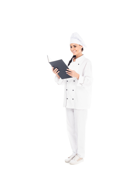 Vue complète du chef souriant en uniforme livre de lecture isolé sur blanc
 - Photo, image