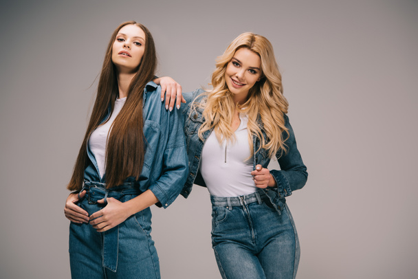 blonde and brunette women in denim clothes smiling and looking at camera  - 写真・画像