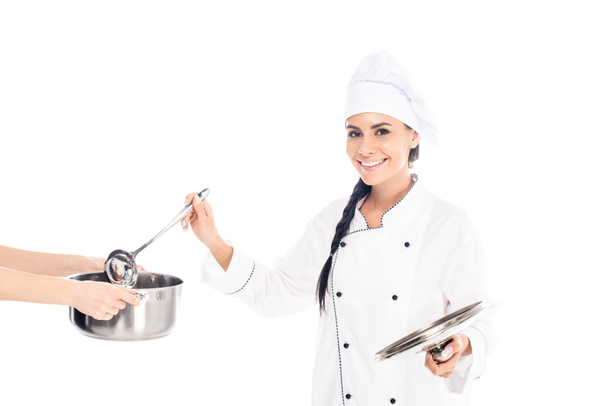 Χαμογελώντας σεφ βυθίζοντας κουτάλα σε κατσαρόλα που απομονώνονται σε λευκό - Φωτογραφία, εικόνα