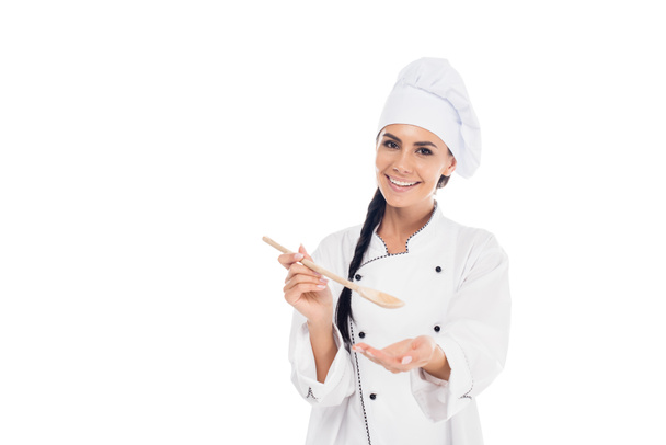Χαμογελώντας σεφ στο καπέλο κρατώντας ξύλινο spatula απομονωθεί σε λευκό - Φωτογραφία, εικόνα