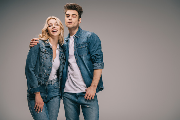 boyfriend and smiling girlfriend in denim clothes hugging and looking at camera  - Foto, Imagen