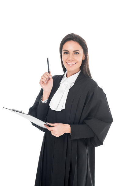 Smiling judge in judicial robe holding clipboard and pen isolated on white - 写真・画像