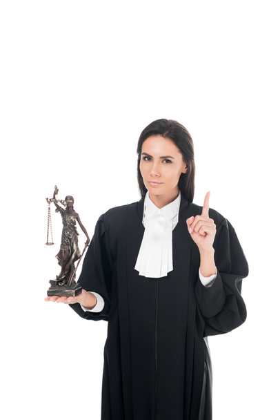 Δικαστής στο δικαστικό ρόμπα κρατώντας ειδώλιο του Θέμης και δείχνοντας χειρονομία ιδέα που απομονώνονται σε λευκό - Φωτογραφία, εικόνα
