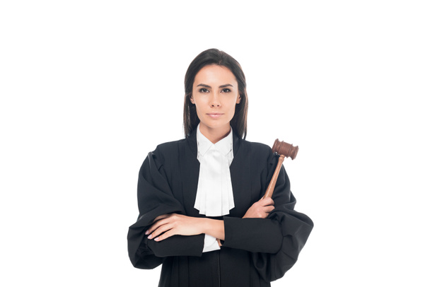 Juez en bata judicial sosteniendo mazo y de pie con los brazos cruzados aislados en blanco
 - Foto, Imagen