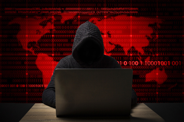hacker in a jacket with a hood with a laptop sits at the table. Added identity theft icons, account hijacking, bank data theft and world map - Photo, Image
