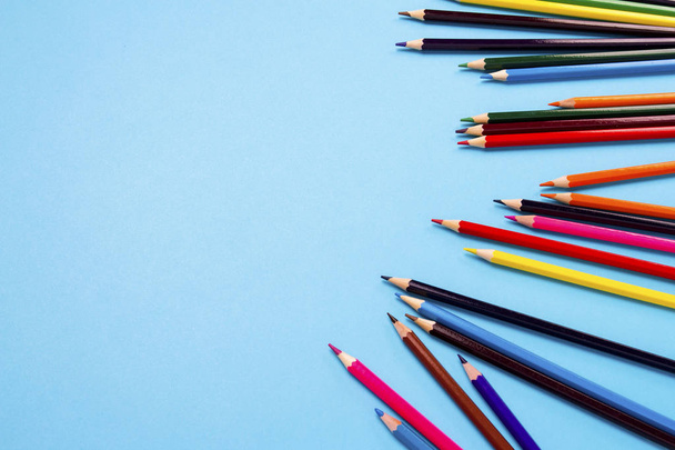 Цветные карандаши, разбросанные на голубом фоне
 - Фото, изображение