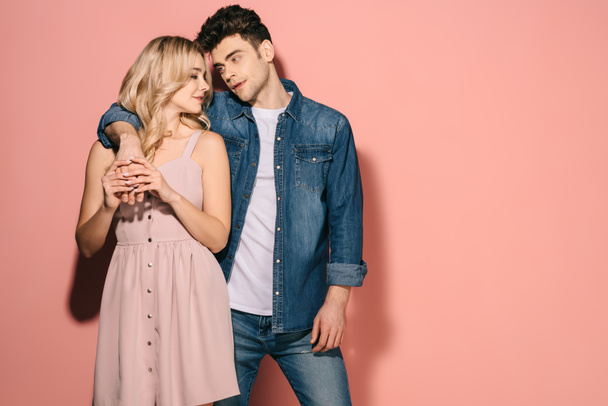 girlfriend in pink dress and handsome boyfriend in denim shirt hugging and looking at each other  - Foto, Bild