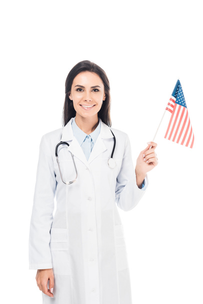 Médecin souriant avec stéthoscope tenant le drapeau américain isolé sur blanc
 - Photo, image