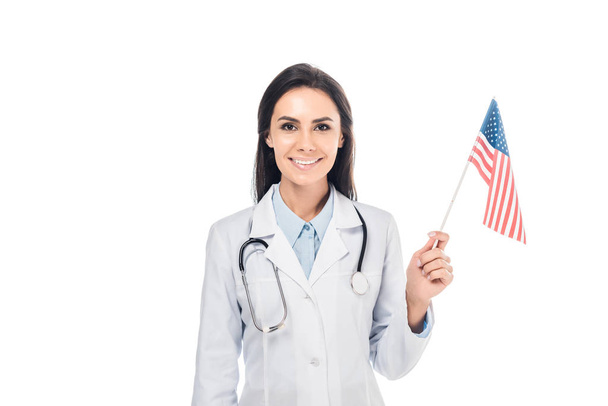Smiling doctor with stethoscope holding american flag isolated on white - Photo, Image