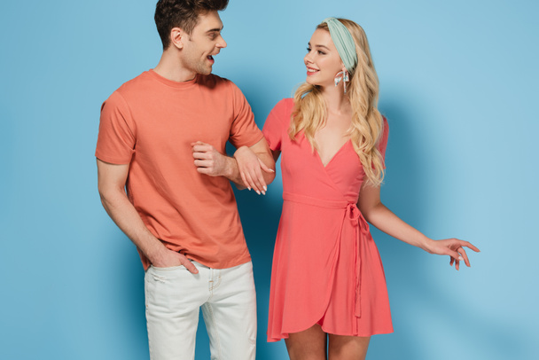 blonde woman in elegant dress and handsome man holding hands and looking at each other  - Foto, afbeelding