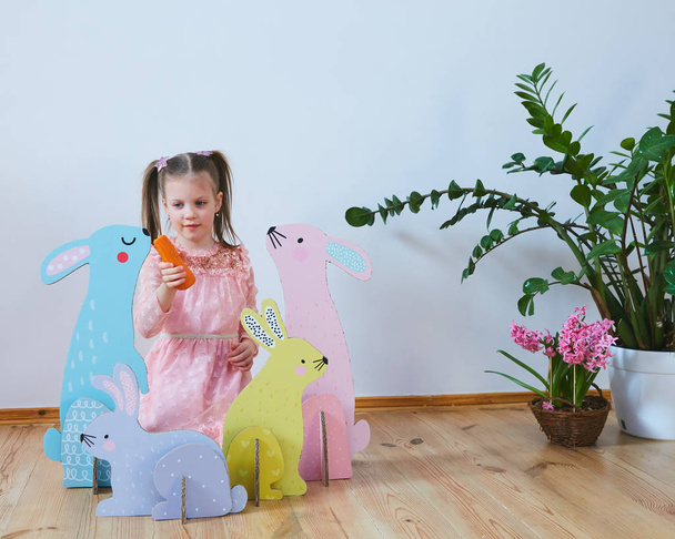 Easter 2019 Beautiful little girl in a dress with Easter decorations. Big Easter bunnies. A lot of different colorful Easter decor. Multicolored decor - Foto, Bild