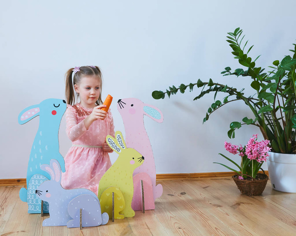 Easter 2019 Beautiful little girl in a dress with Easter decorations. Big Easter bunnies. A lot of different colorful Easter decor. Multicolored decor - Photo, image