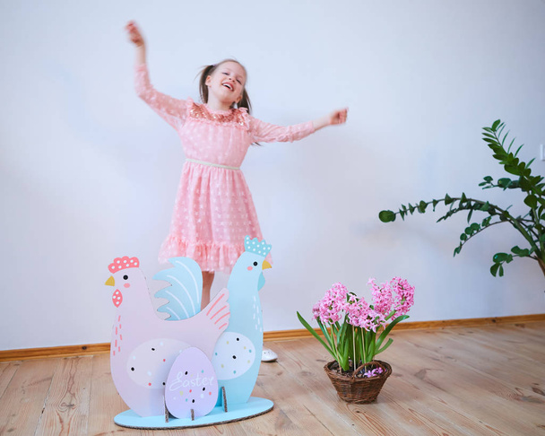 Easter 2019 Beautiful little girl in a dress with Easter decorations. Big Easter eggs and bunnies, colorful place. A lot of different colorful Easter eggs. Multicolored decor - Foto, Bild