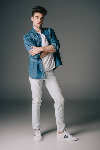 handsome man in denim shirt and jeans with crossed arms looking at camera  - Foto, imagen