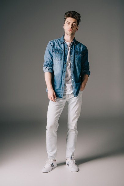 handsome man with hand in pocket in denim shirt and jeans looking at camera  - Foto, Imagen