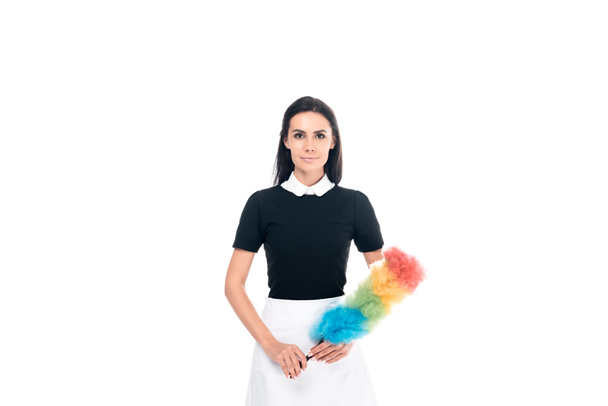 Brunette maid in uniform holding duster isolated on white - Fotó, kép